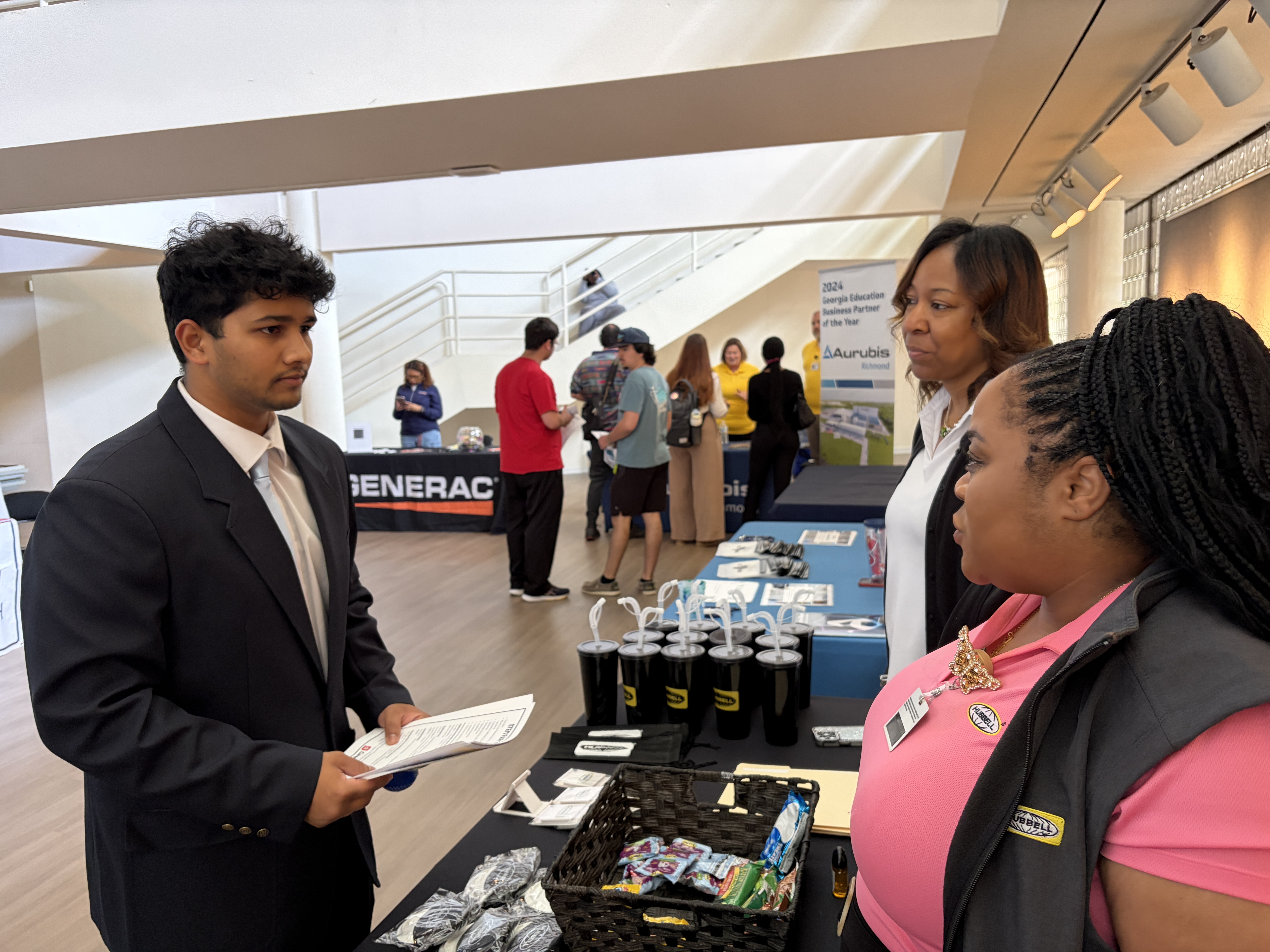 Appa Modugu, a cybersecurity graduate student from Barnwell, S.C. (left), speaks with Tanesha Brown, a recruiter (far left), and Raina Brathwaite, a master scheduler (right), from Hubbell, a manufacturing company based in Aiken.