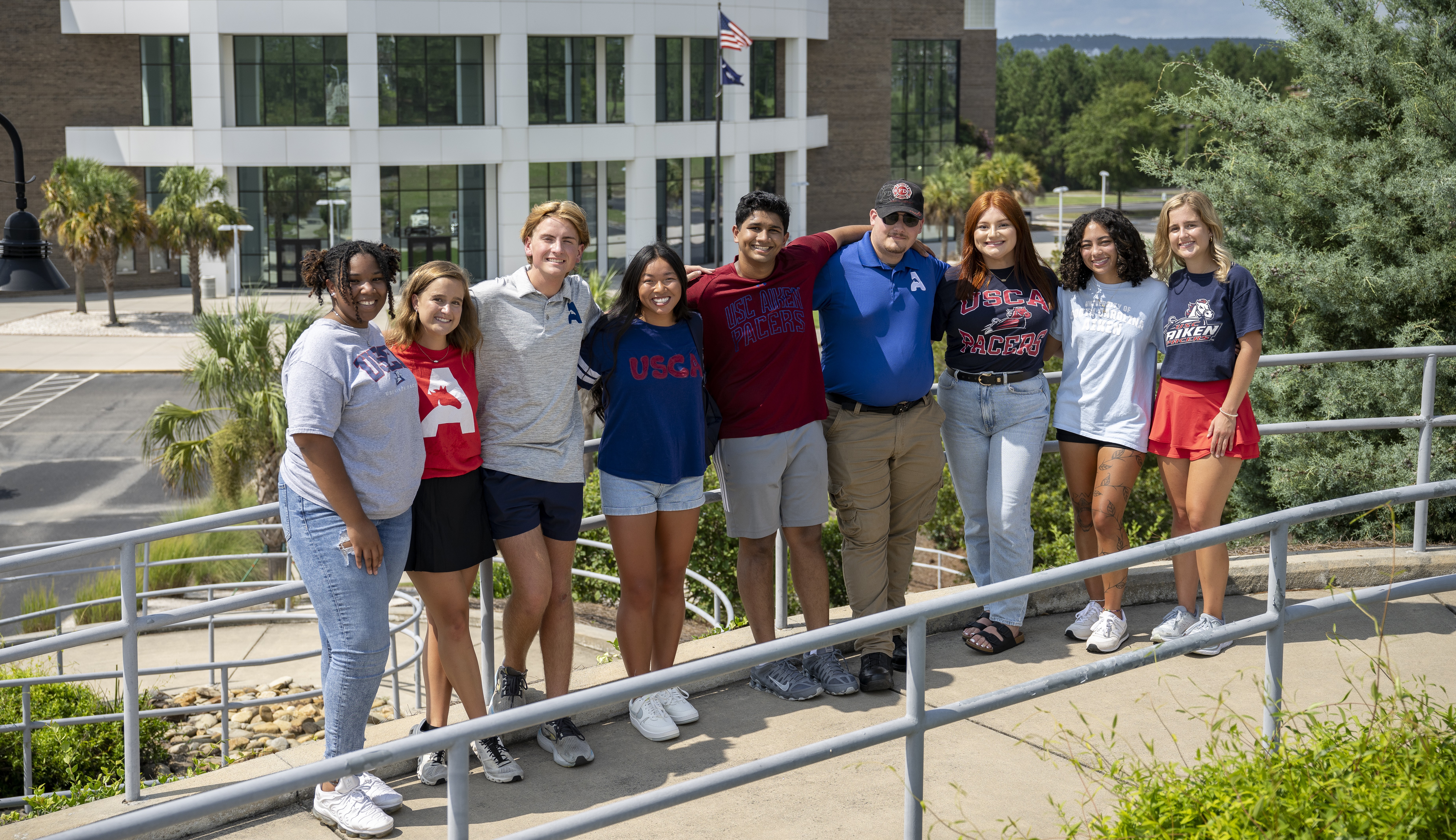 USCA student pose for photo with the Convocation Center in the background