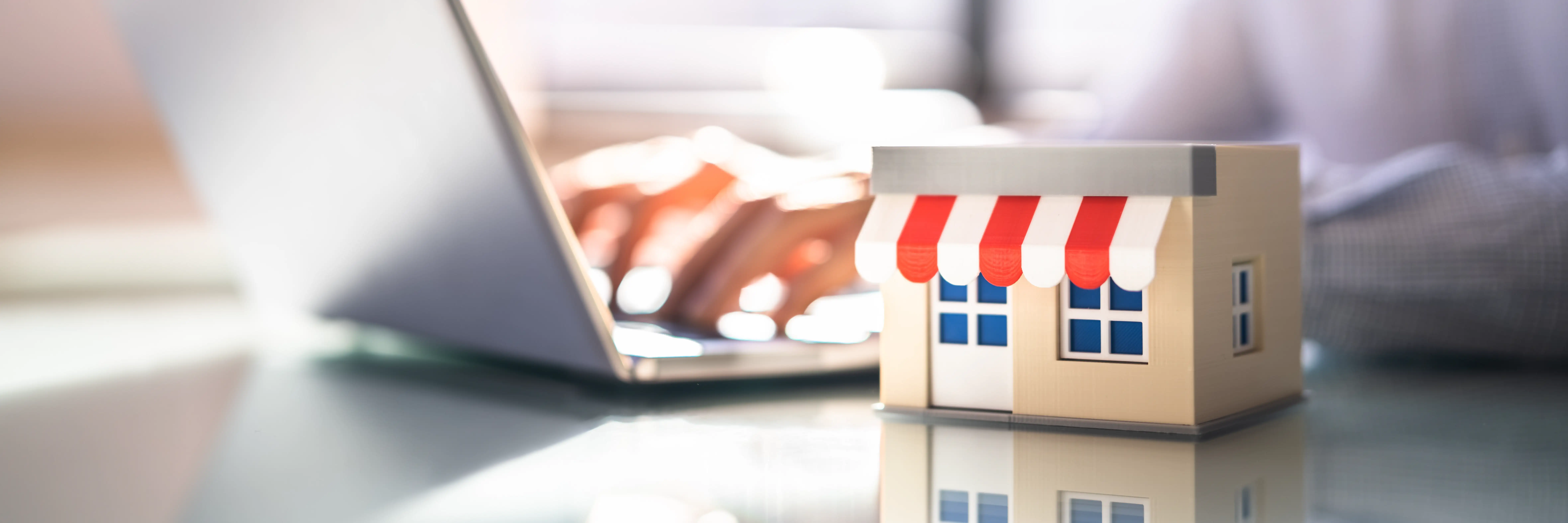 Someone typing on a laptop next to a scale model of a storefront.